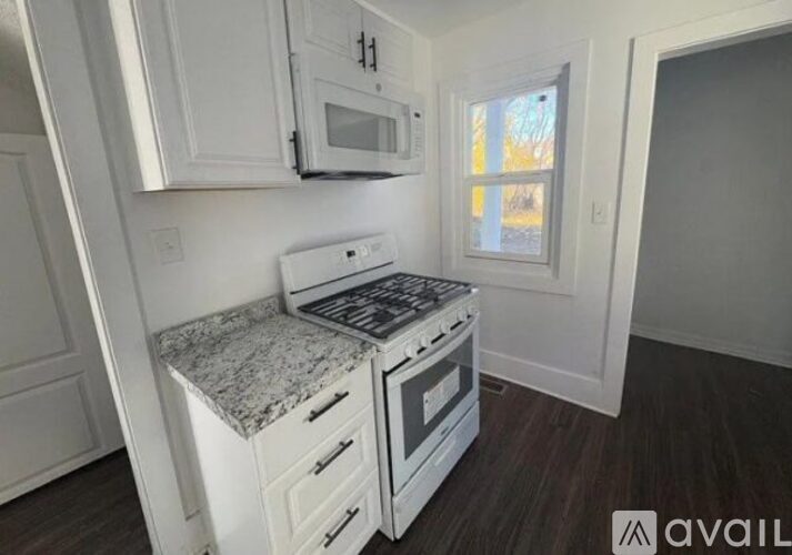 A kitchen with white cabinets and a granite countertop.