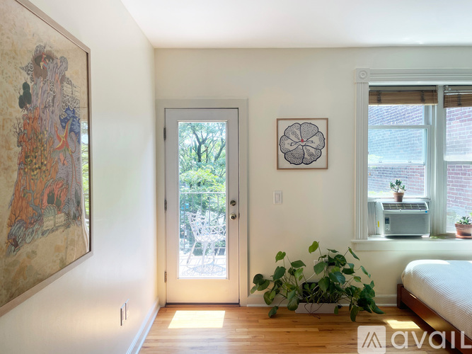 A room with a large painting on the wall and a bed in the corner.