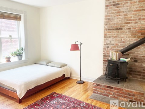 A bedroom with a brick wall and a wood burning stove.