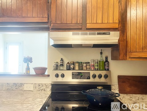 A kitchen with a stove top oven and wooden cabinets.