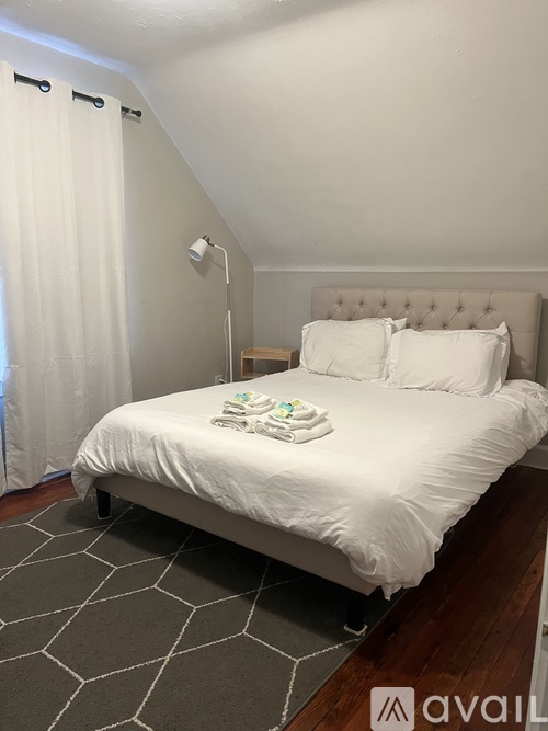 A bedroom with a white bed and a grey carpet.