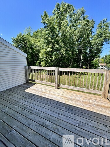 A wooden deck with a fence and trees in the background.