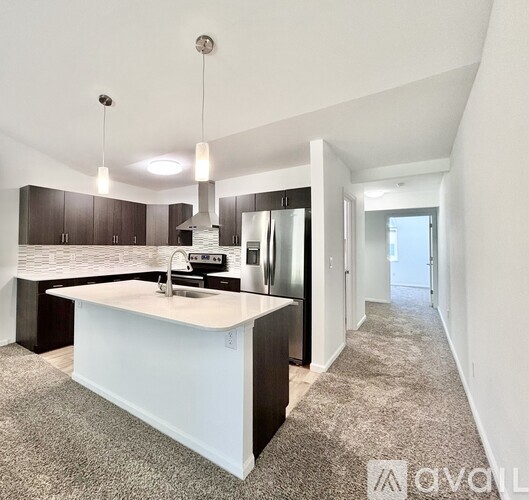 A modern kitchen with a white island and dark brown cabinets.