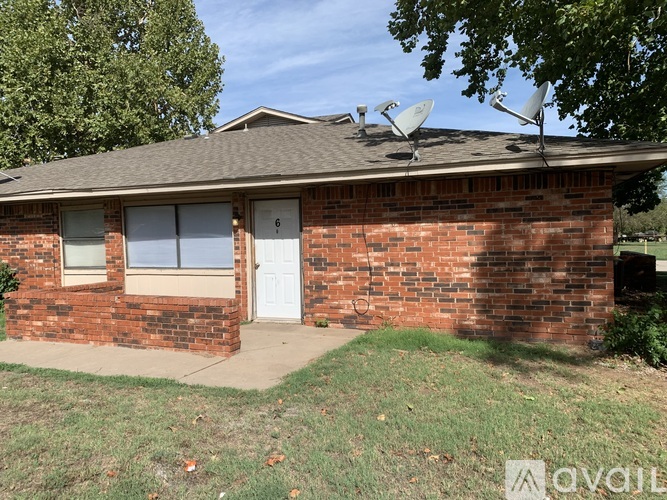 A house with a white door and windows has a brown roof with satellite dishes on it.