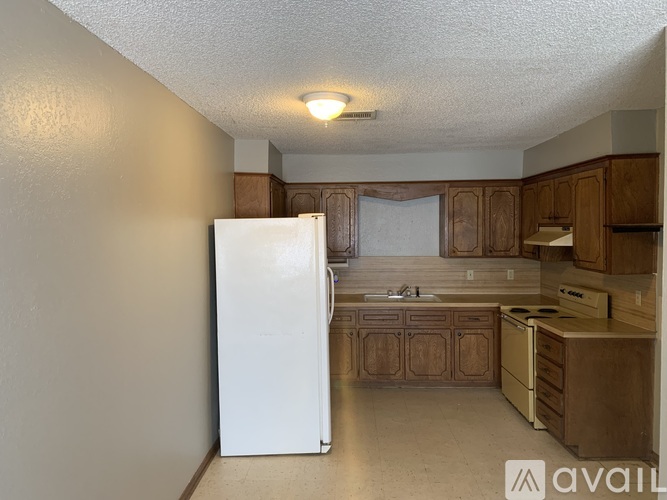 A kitchen with a white fridge and wooden cabinets.