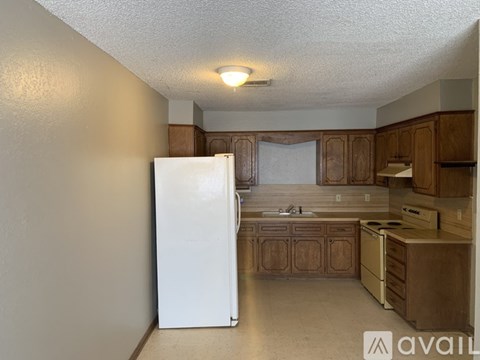 A kitchen with a white fridge and wooden cabinets.
