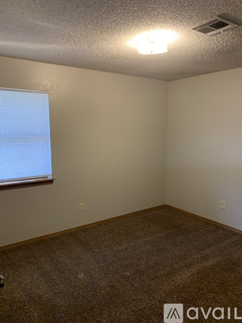 A room with a carpeted floor and a window with blinds.