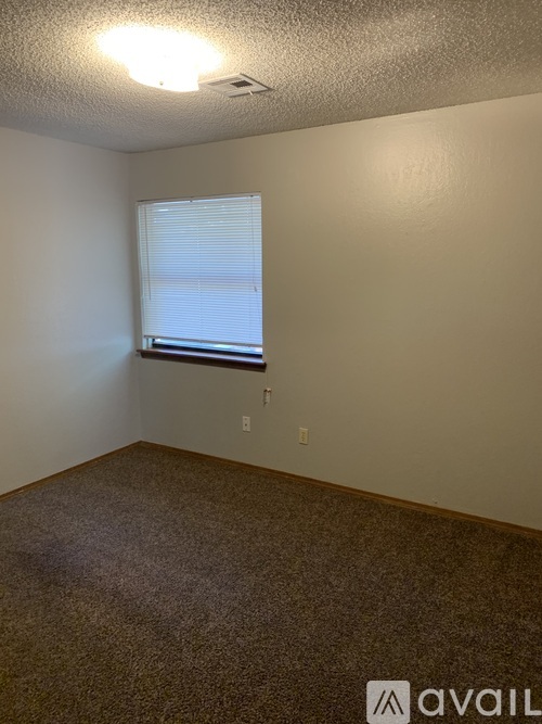 A room with a carpeted floor and a window with blinds.