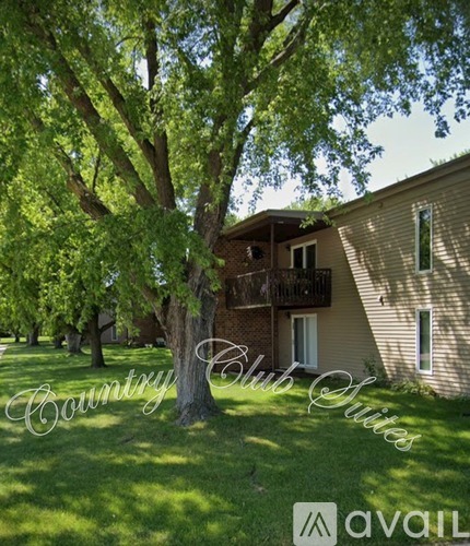 A tree in front of a building with the words "Country Club Suites" written on it.