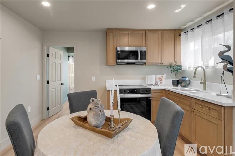 A kitchen with a table and chairs in the foreground and a microwave above the stove.