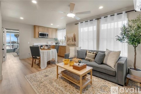 A well-lit living room with a grey sofa, a wooden coffee table, and a dining table set for two.