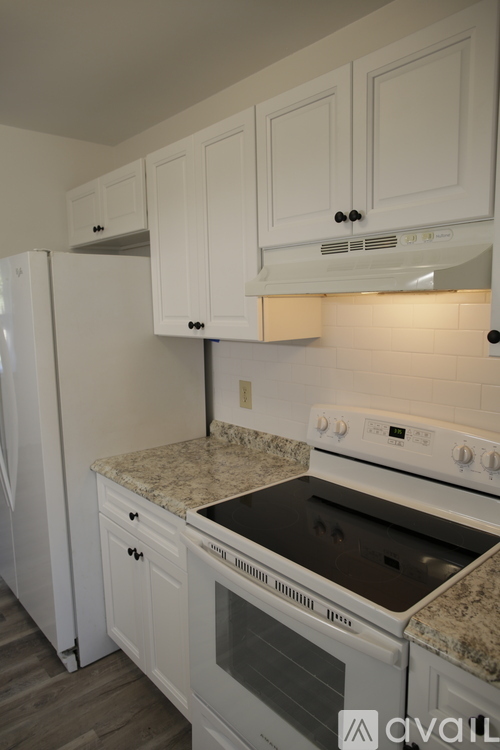 A kitchen with white cabinets and a white stove top oven.