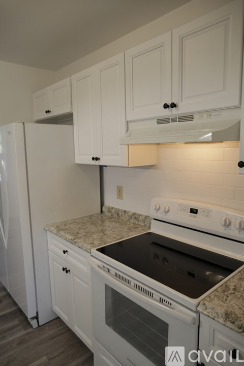 A kitchen with white cabinets and a white stove top oven.