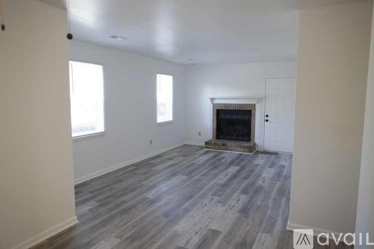 A spacious living room with a fireplace and wood flooring.