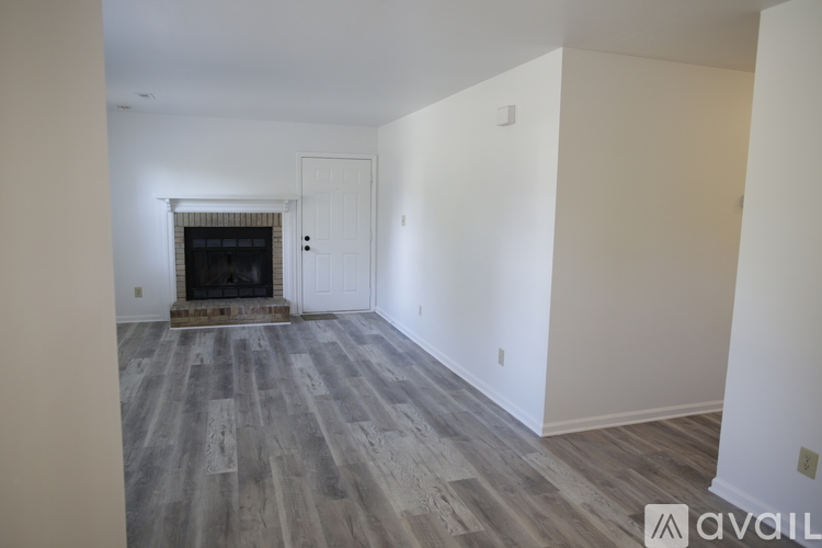 A spacious room with a fireplace and wood flooring.