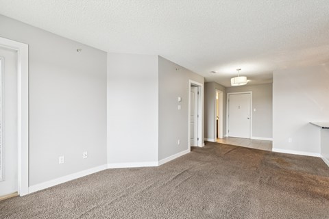 A spacious room with carpeted floor and white walls.