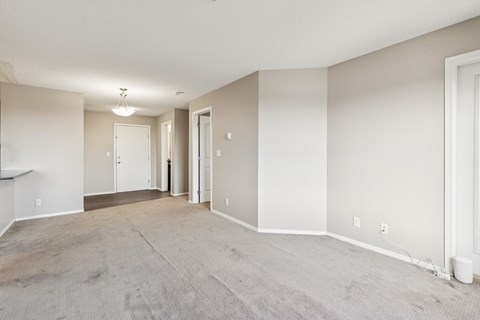 A spacious room with carpeted floor and white walls.