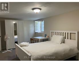 A bedroom with a bed, desk, and fan.