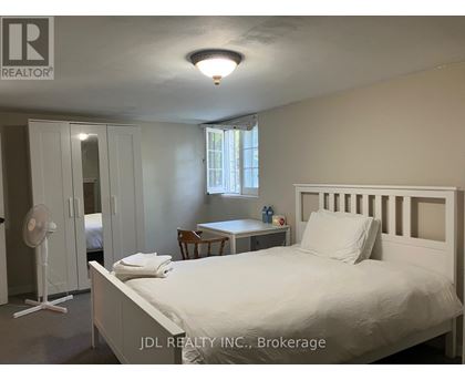 A bedroom with a bed, desk, and fan.