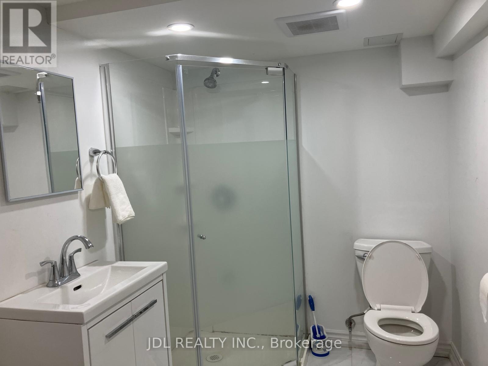 A bathroom with a toilet, sink, mirror, and shower.