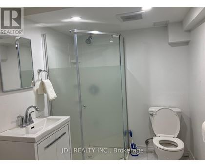 A bathroom with a toilet, sink, mirror, and shower.