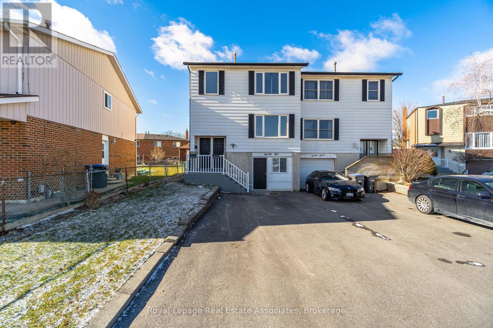 A real estate photo shows a two-story building with a garage and a car parked in front.