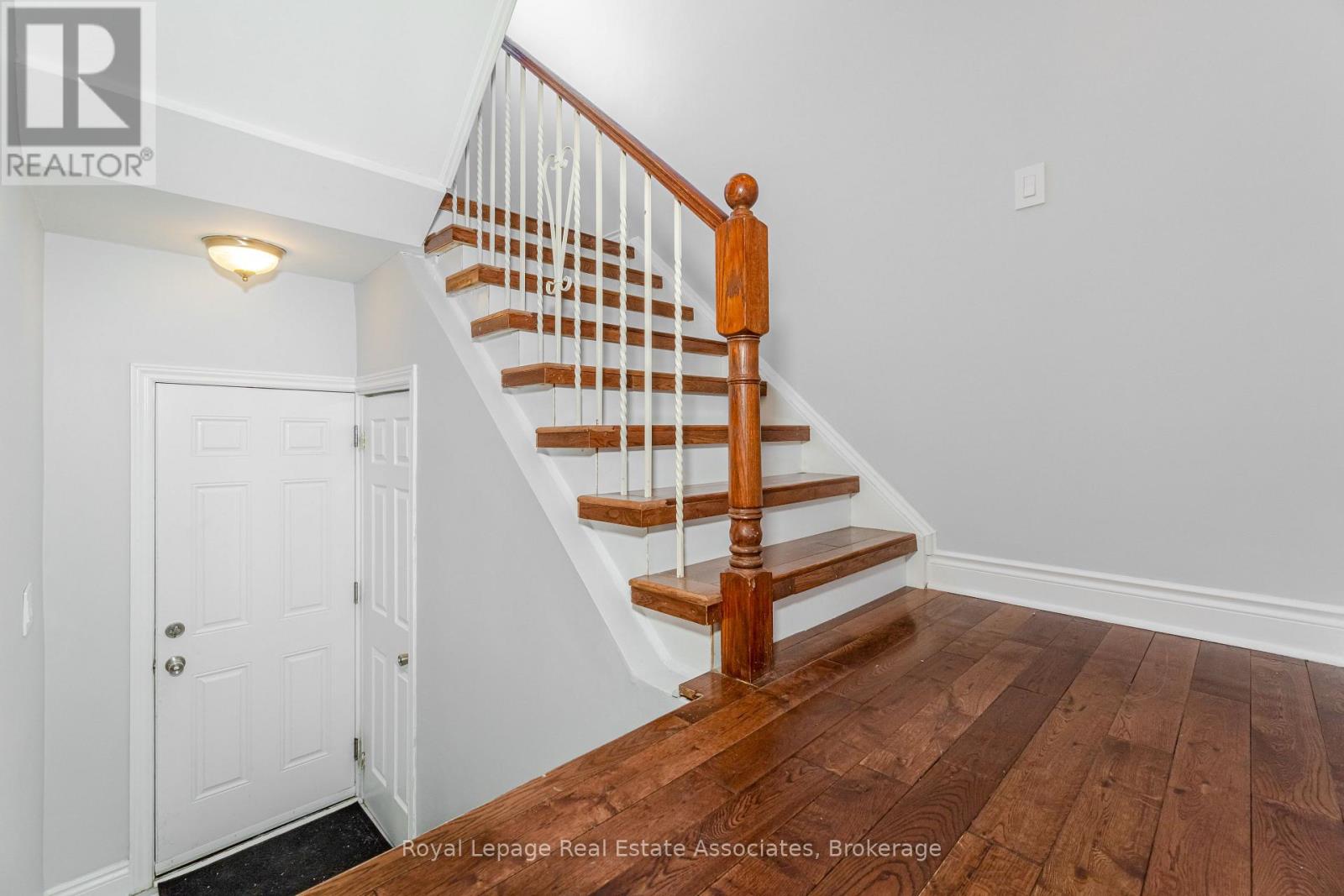A wooden staircase with a white railing and a white door.
