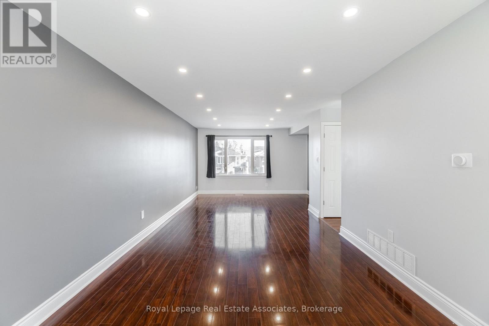 A spacious room with wooden floors and white walls.