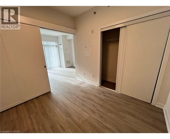 A room with wooden flooring and a doorway leading to another room.