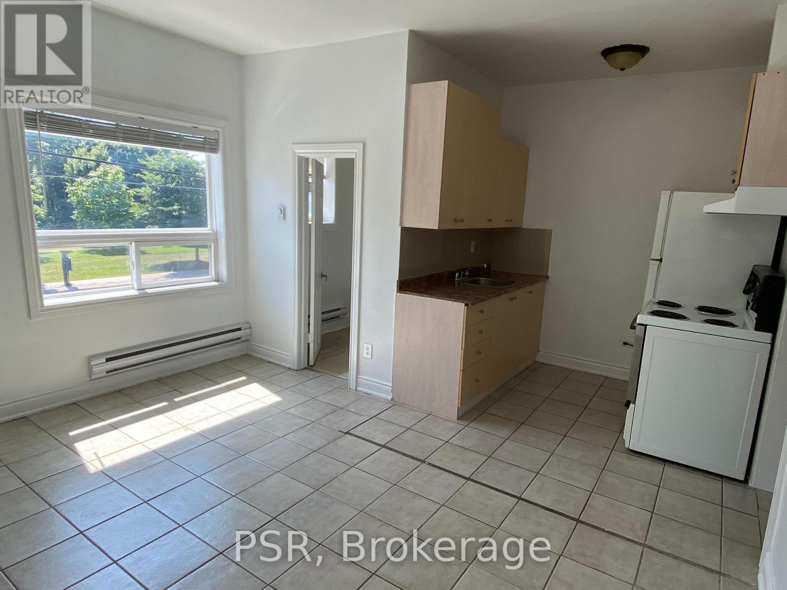A kitchen with a window and a door leading to another room.