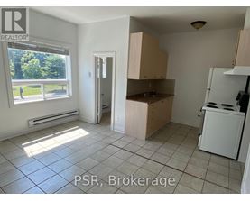A kitchen with a window and a door leading to another room.