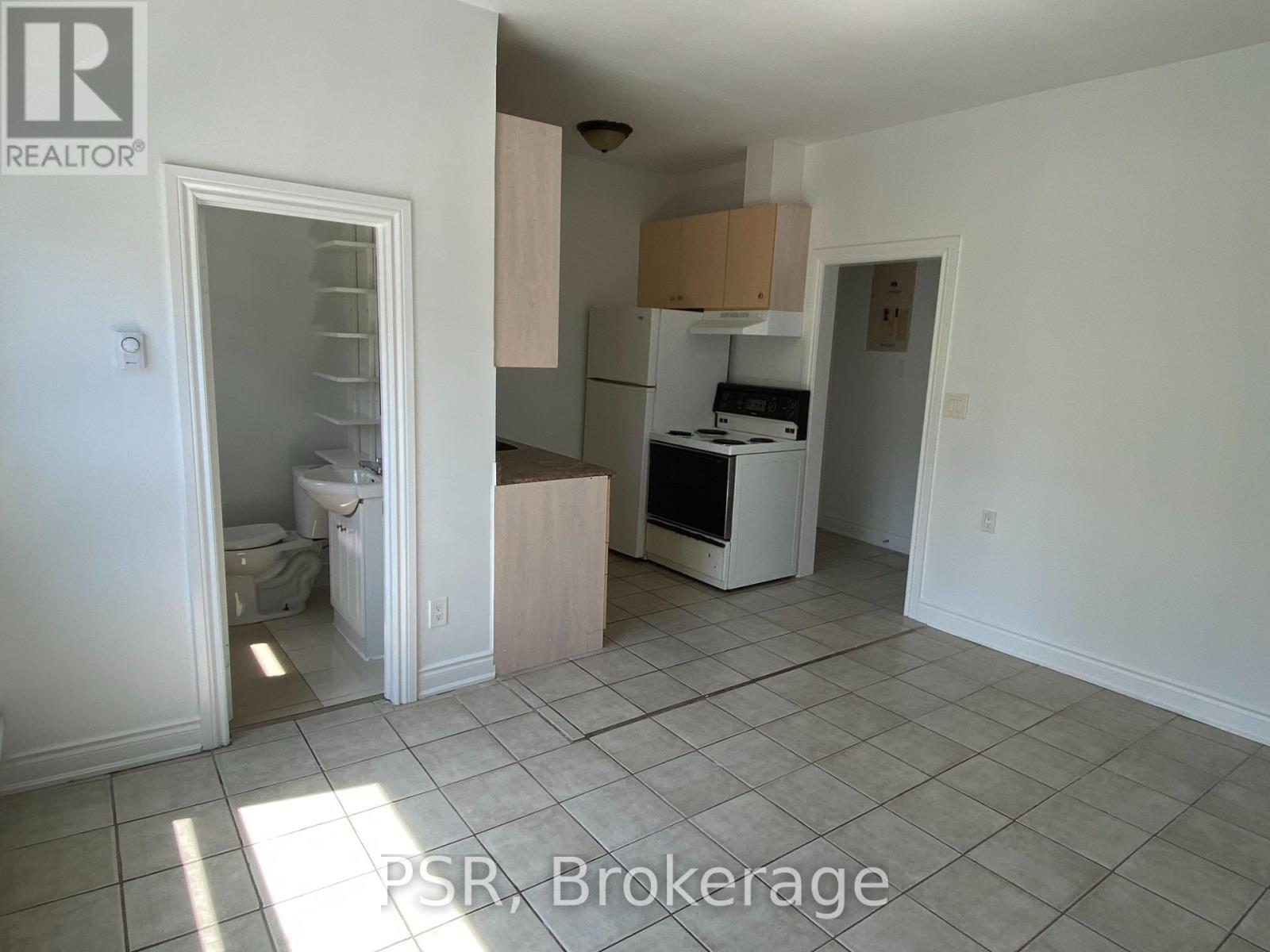 A kitchen with white appliances and a tile floor.