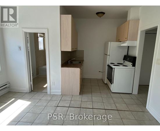 A kitchen with a refrigerator, sink, and cabinets is for sale.
