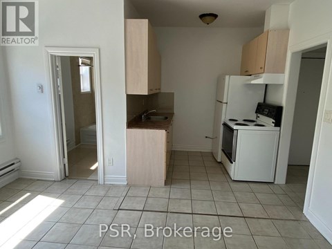 A kitchen with a refrigerator, sink, and cabinets is for sale.