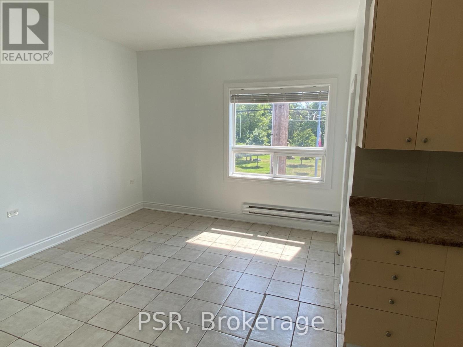 A room with a window showing a view of trees and a tiled floor.