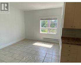 A room with a window showing a view of trees and a tiled floor.