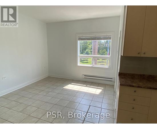 A room with a window showing a view of trees and a tiled floor.