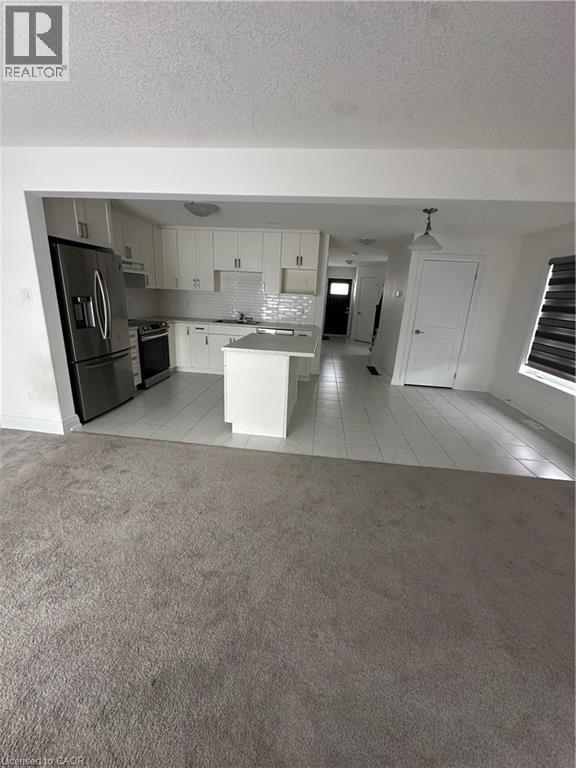 A kitchen with white cabinets and a black fridge.