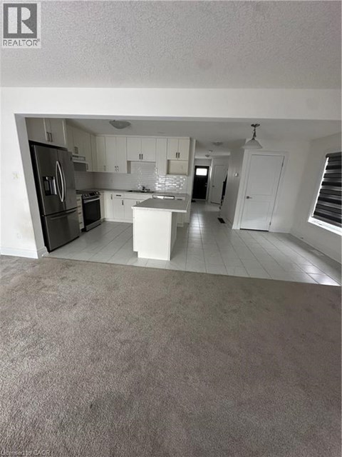 A kitchen with white cabinets and a black fridge.