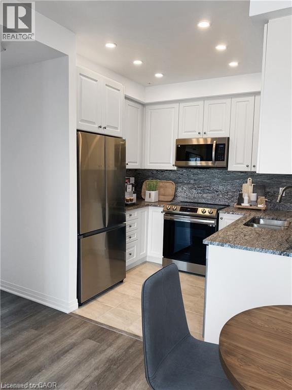 A kitchen with a refrigerator, oven, and microwave.