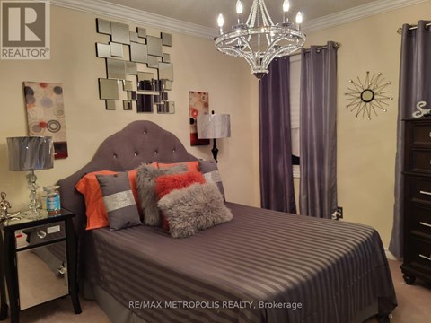 A bedroom with a bed, a chandelier, and a mirror on the wall.