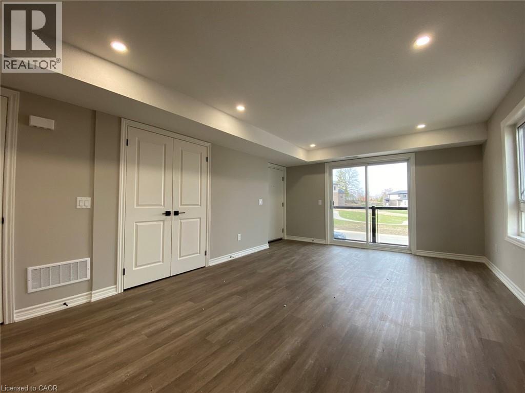 A spacious room with wooden flooring and a sliding glass door leading to a balcony.