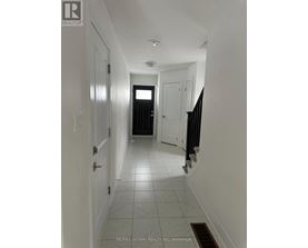 A hallway with white walls and tile flooring.