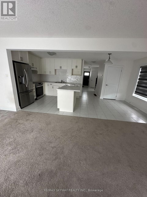 A kitchen with white cabinets and a black fridge.