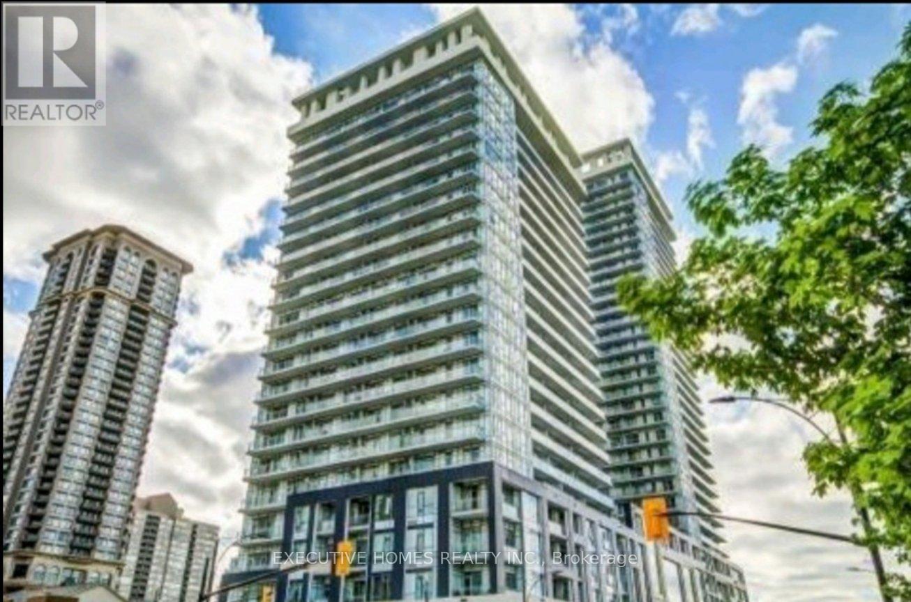 A tall building with many windows is surrounded by other buildings.