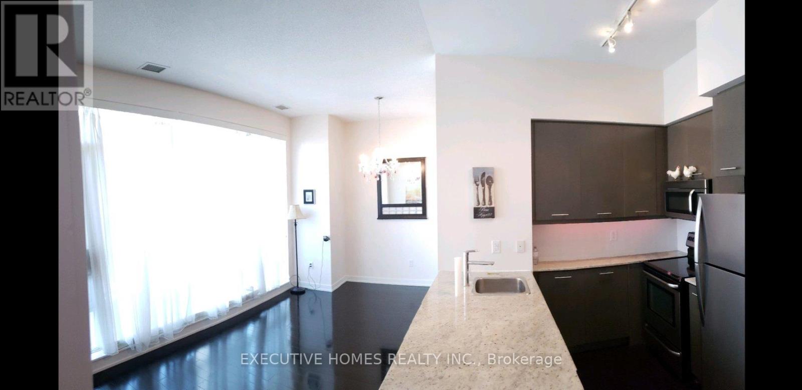 A modern kitchen with dark wood cabinets and a marble countertop.