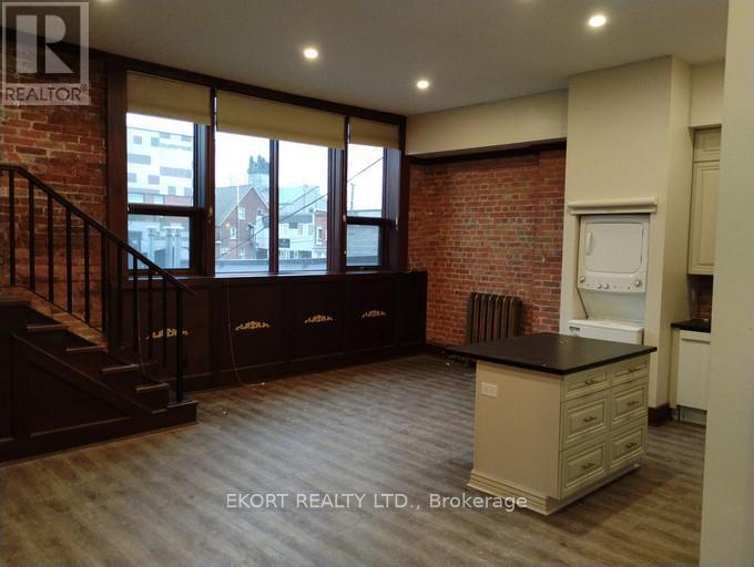 A kitchen area with a brick wall and wooden flooring.
