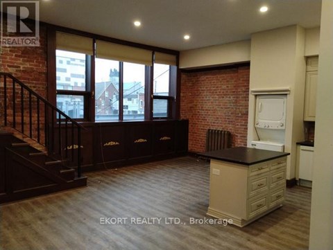 A kitchen area with a brick wall and wooden flooring.