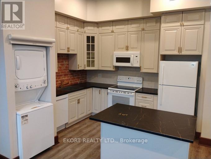 A kitchen with white appliances and a black countertop.
