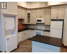 A kitchen with white appliances and a black countertop.